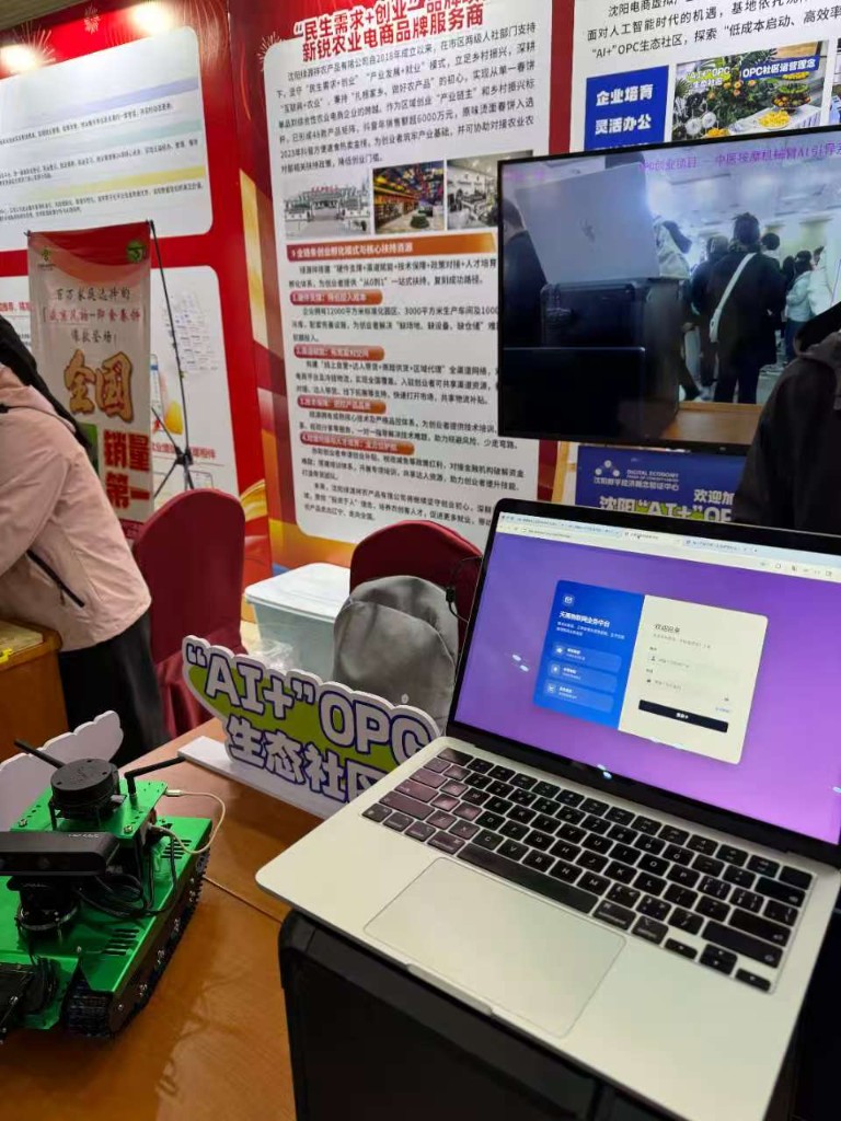 展位桌面：沈阳 AI+OPC 社区标识、社区成员制作的硬件 demo、笔记本屏幕显示天禹物联网 AI 客服业务中台